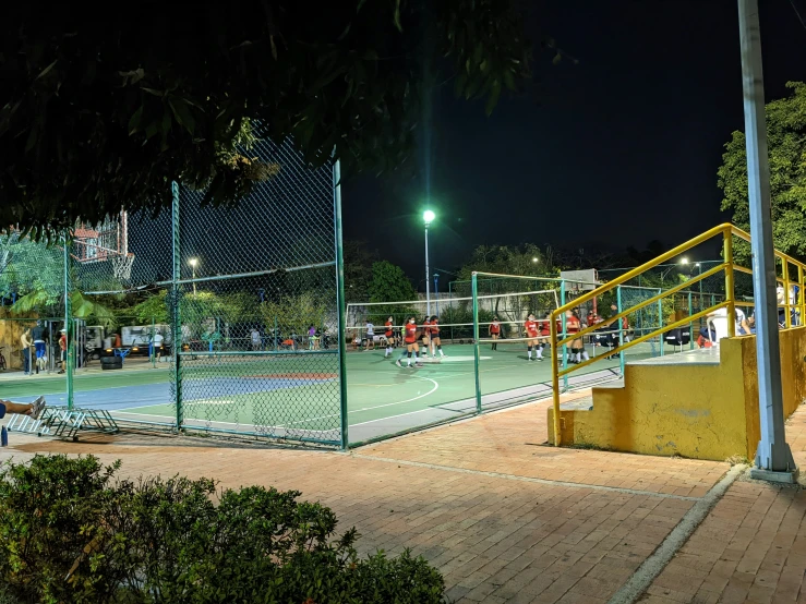 a group of s play on a brightly lit tennis court