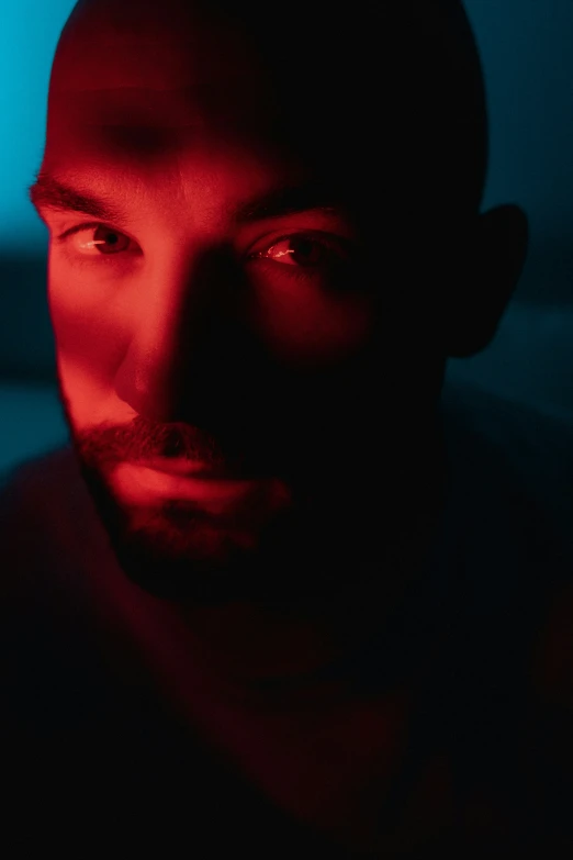 a man staring off into the distance in dark with red lighting