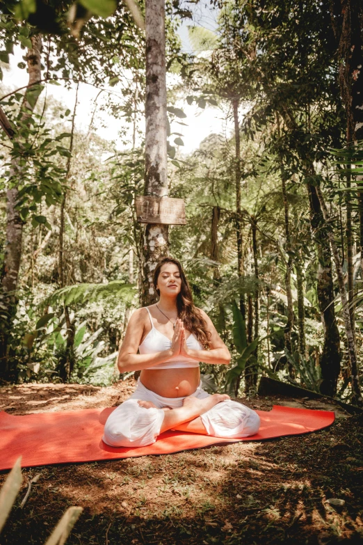 the lady is sitting on the blanket in the forest