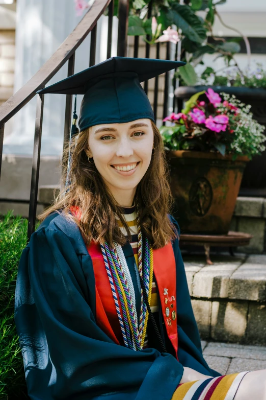 a female graduate sitting outside in her cap and gown