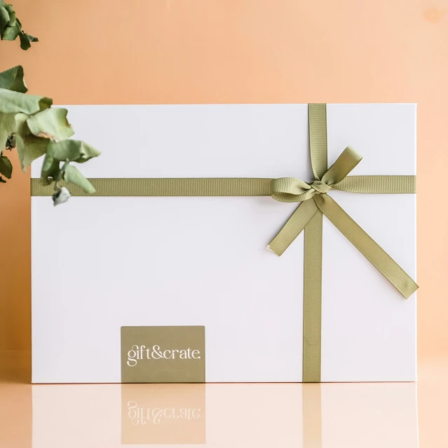 a white gift box with a gold bow and name tag