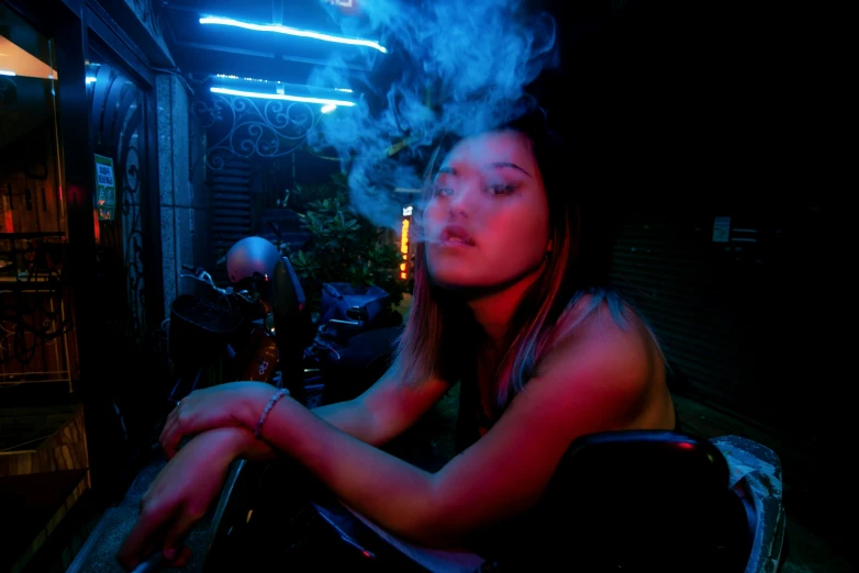 a woman sitting in the dark smoking a cigarette