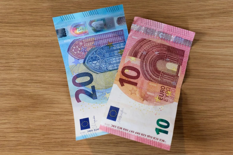 two japanese currency notes sit on a wooden table