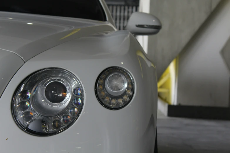 the front of a silver sports car with its lights on