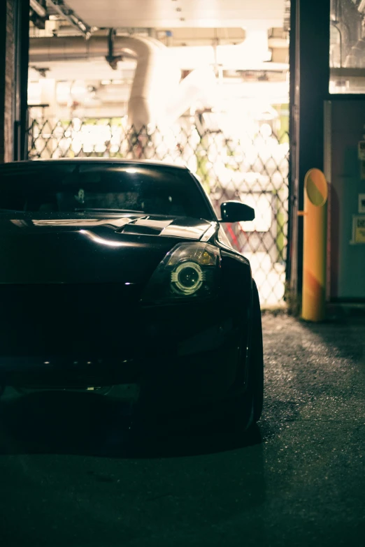 the black car is parked near the chain link fence