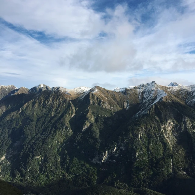 some snow capped mountains are shown with clouds in the background