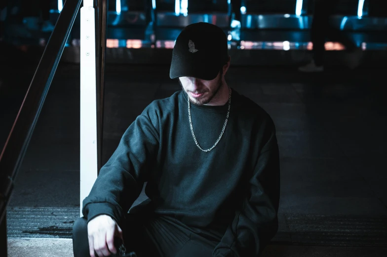 a man sits on a step at night in a cap and sweater