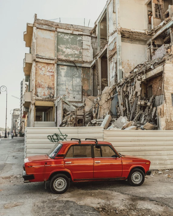 the rusted old vehicle is parked outside an old building