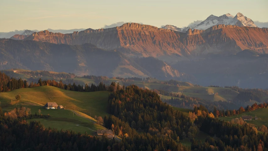 a mountain range with green grassy field and trees