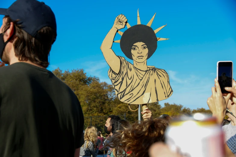 a large crowd of people watching a woman with a sign in her hand