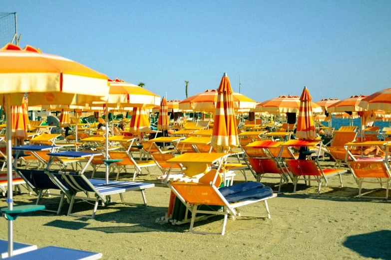 many orange and blue beach chairs with colorful umbrellas in the sand