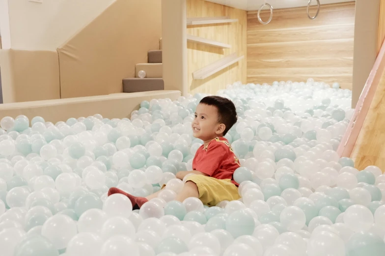 a child sitting in a ball pit filled with balloons