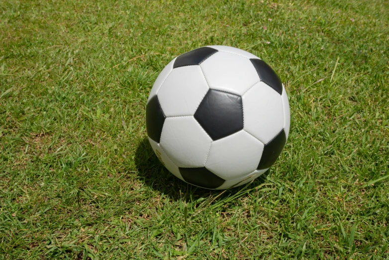 a large white and black soccer ball laying on the grass