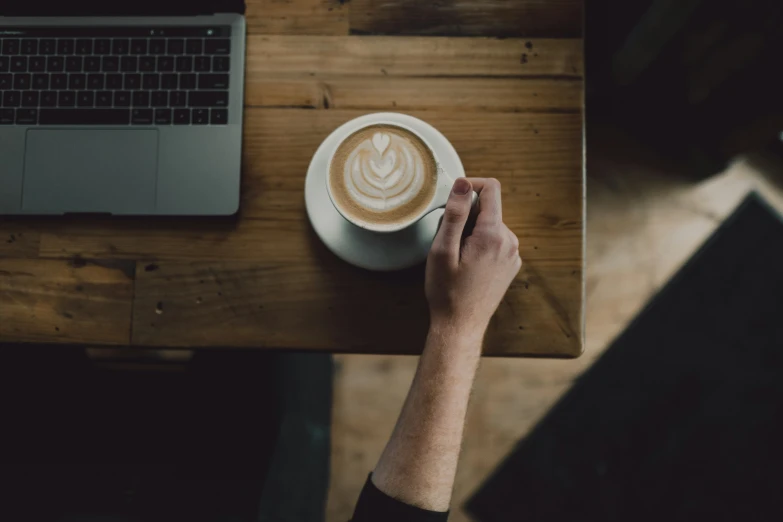 a person sitting at a table with a cup of coffee on their lap