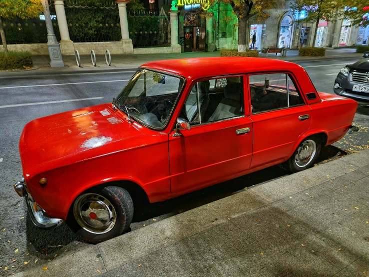 an old red car parked next to some sidewalk