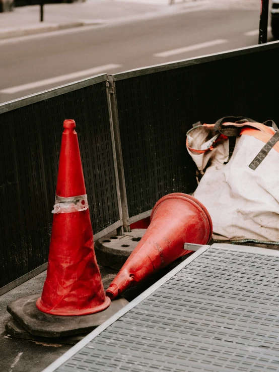 a bag and cone sitting on a sidewalk in front of a metal gate