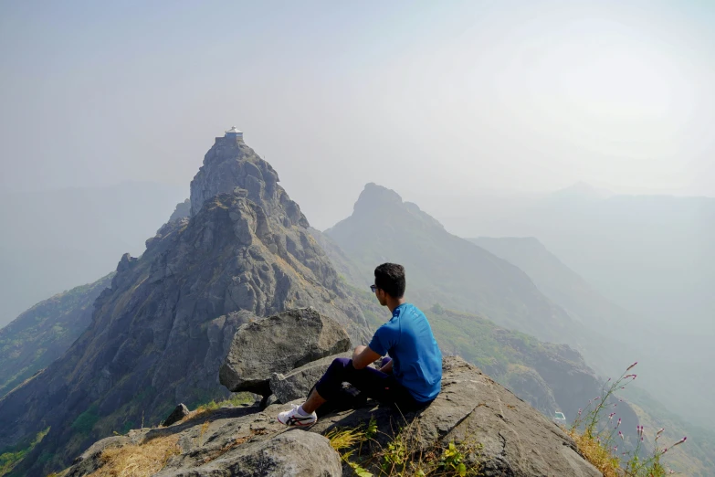 a man is sitting on top of a mountain