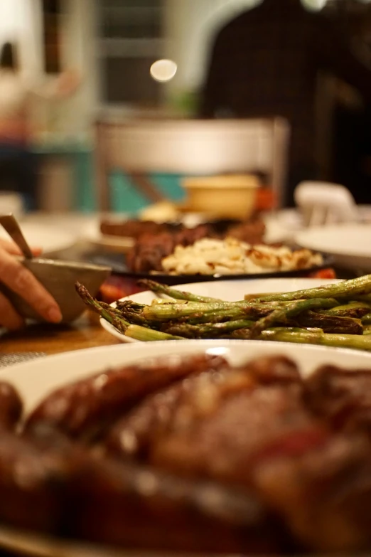 someone  a steak on top of a table with green asparagus