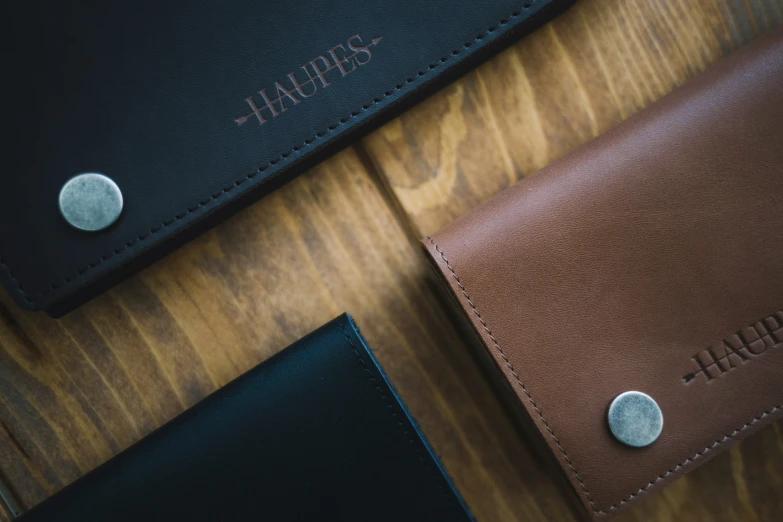 two brown leather wallets with names on them