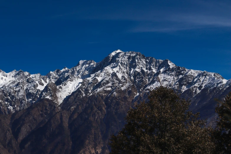 snow - capped mountains against a blue sky stand in the foreground