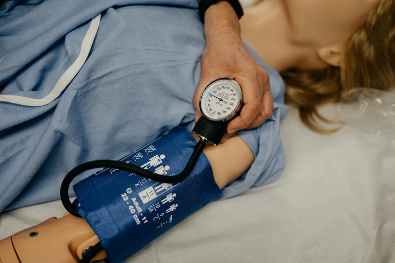 an aed training dummy with a person with  pressure meter in the arm