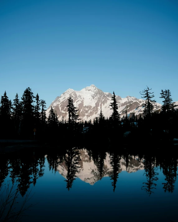 the snow capped mountain is silhouetted against a clear blue sky