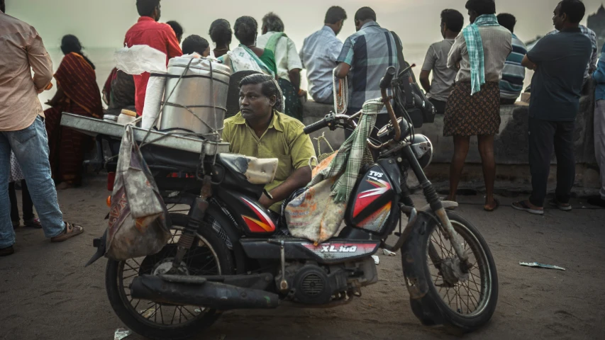 a man sitting on top of a motorcycle holding a bag