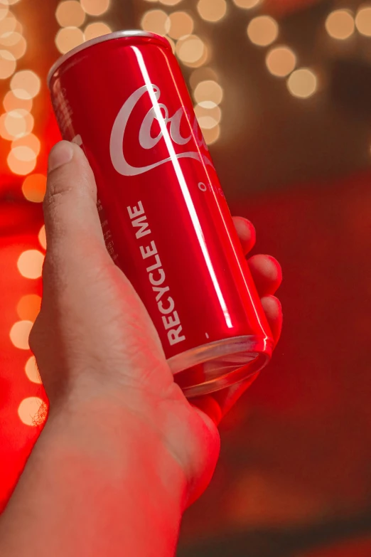 a hand holding an almost empty coca - cola can