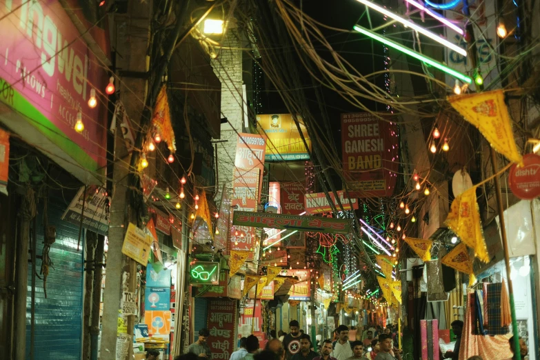 people walking through the colorful stores at night