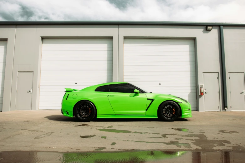 a green car is parked in front of a white garage