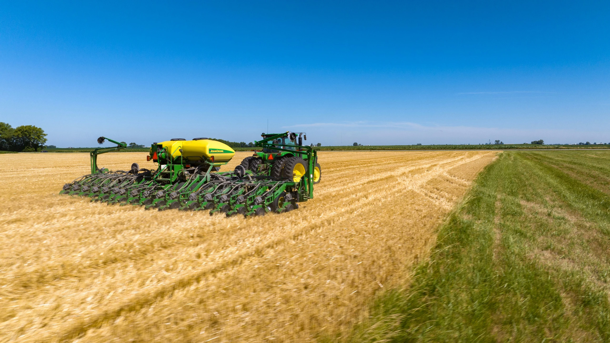 two people on a tractor with a sprayer in the middle of the field