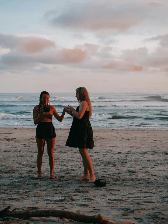 two girls in dress playing with each other on a beach