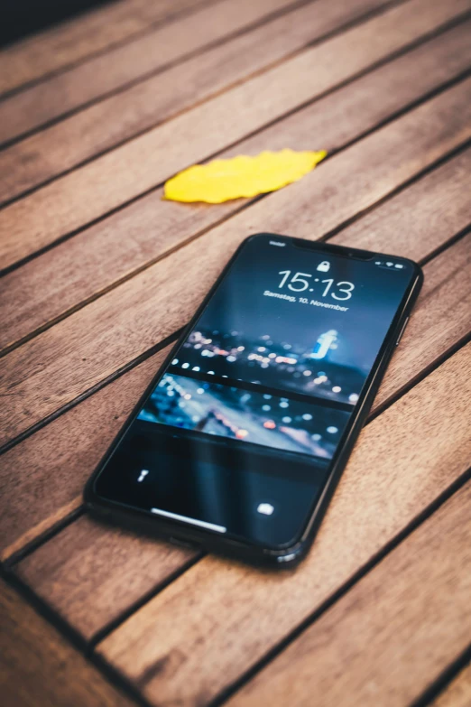 a phone sitting on a wooden table next to a piece of yellow paper