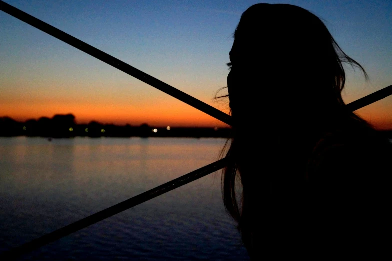 the woman's back is standing against an ocean