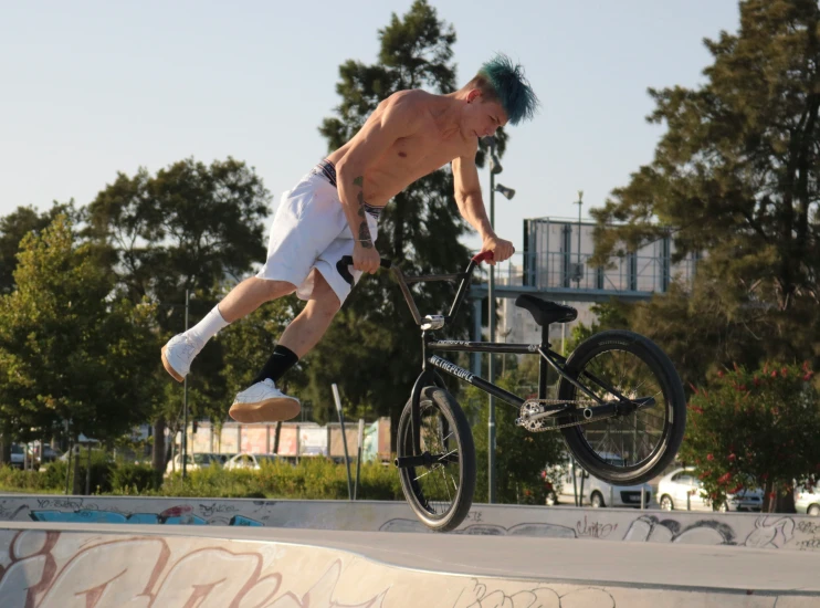 a shirtless boy is doing a trick on his bicycle