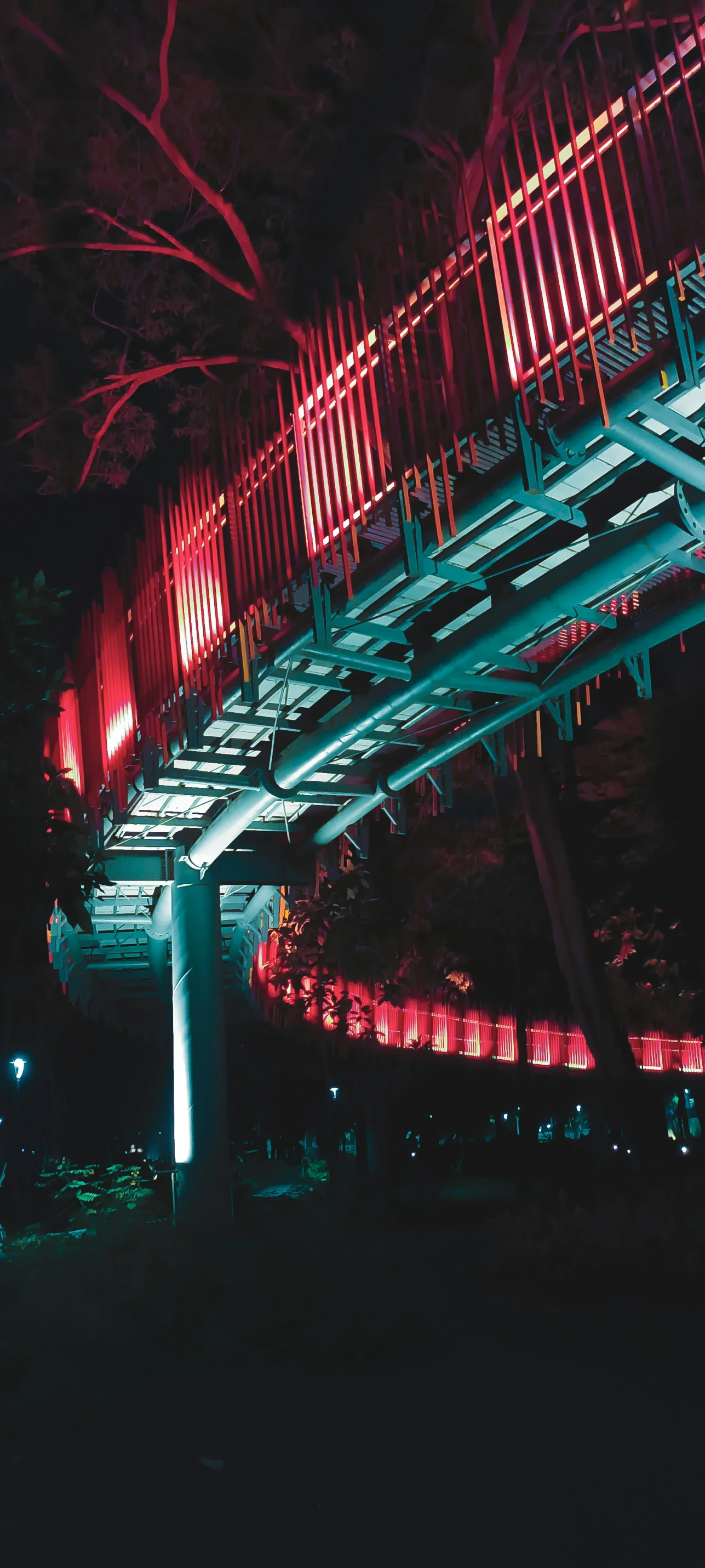 a red light shines under a lit bridge