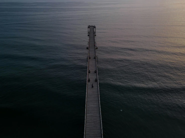 a long dock in the water at sunset