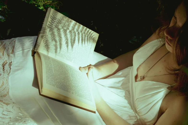 a woman reading a book lying on a pillow