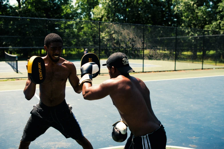 two young men practice boxing on a court
