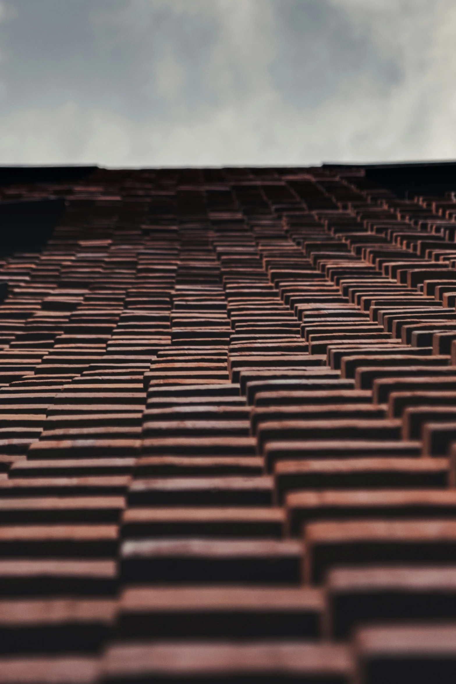 a brick wall and sky with small clouds in the background