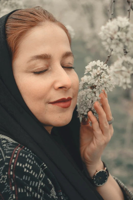 a woman in black clothes is holding a white flower