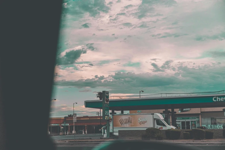 a large gas station with a sky and clouds