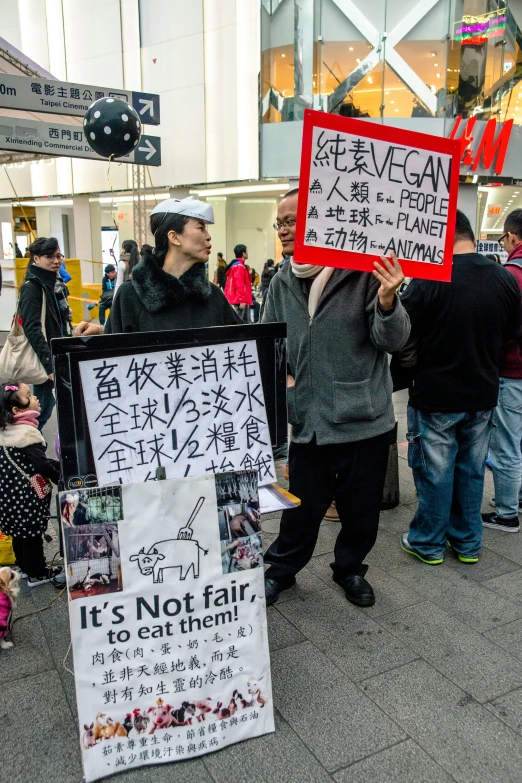 a crowd of people standing next to each other holding signs