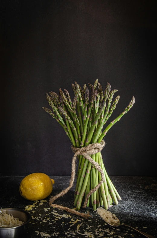 asparagus tied to each other with yellow fruit behind them