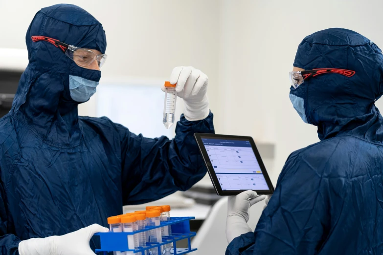 two people in black jackets and masks holding up some orange beaks