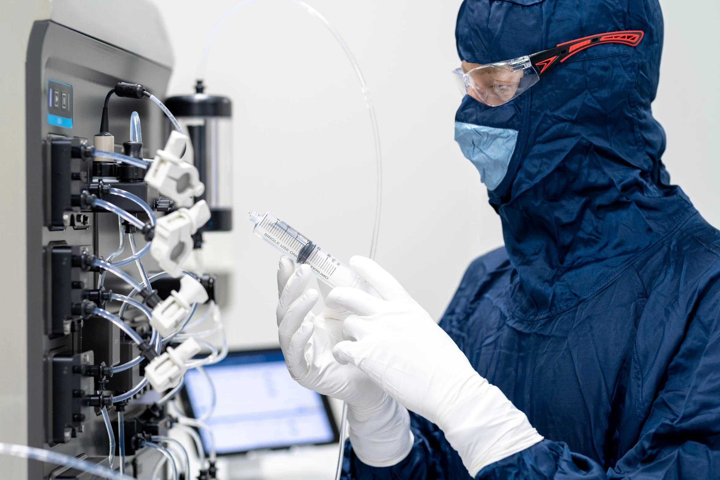 an employee is holding a tube while the equipment in front of him