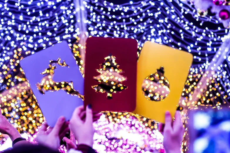 three people are holding up brightly decorated cards