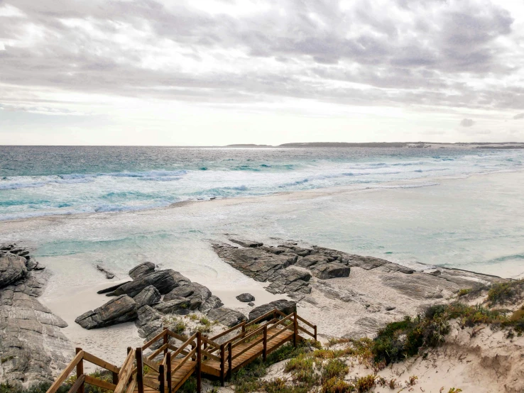 a view of a beach and stairs from the top of some rocks