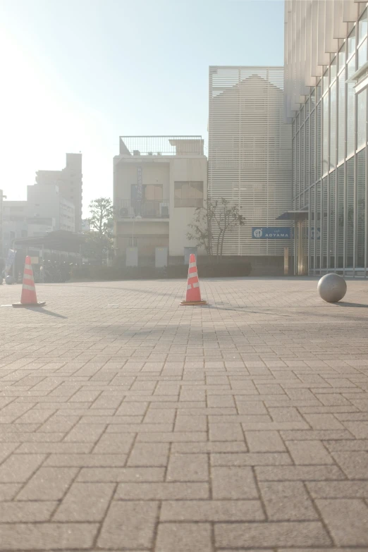 the empty street has traffic cones with building in background