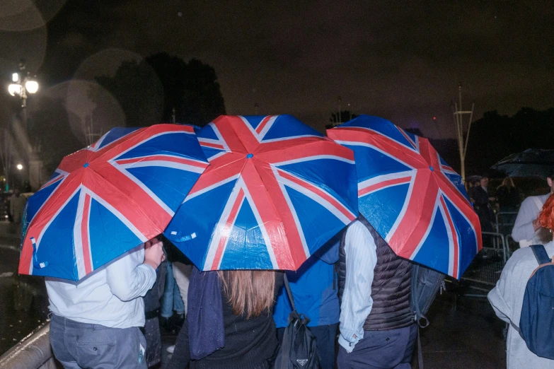 people are carrying union jack flags covered by umbrellas